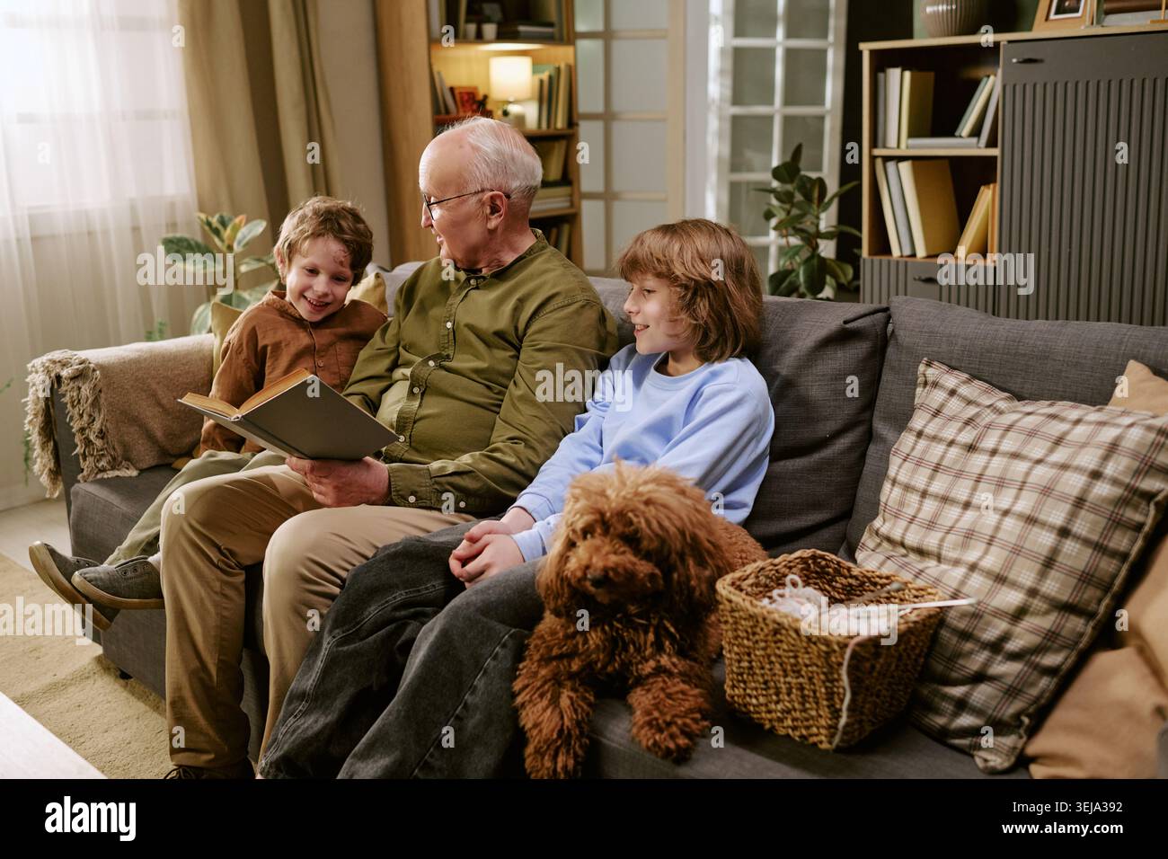 Senior Mann liest mit Kindern zu Hause für Familienbindung Stockfoto