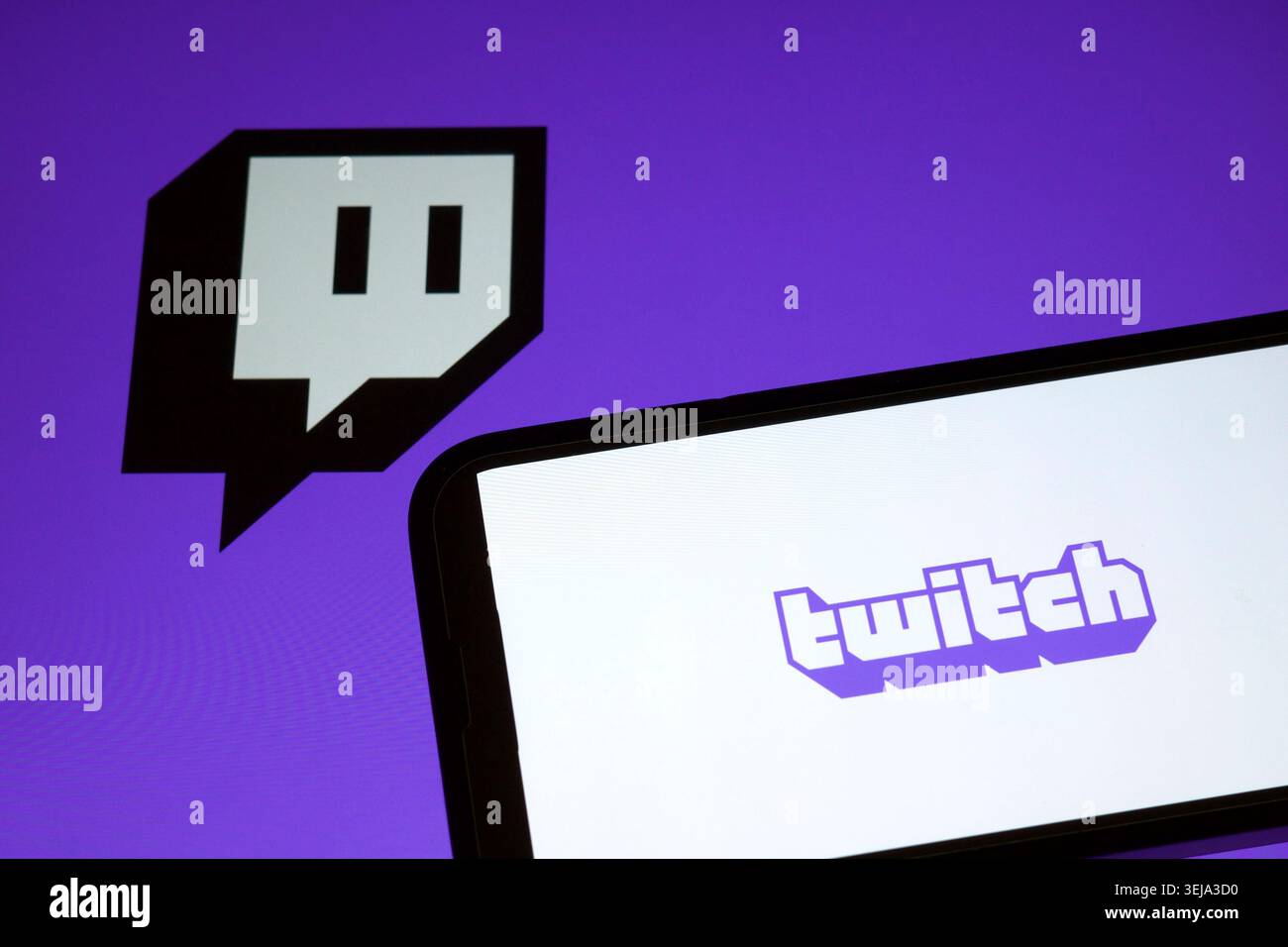 Das Twitch-Logo wird auf einem Smartphone-Bildschirm mit dem Twitch-Logo im Hintergrund angezeigt Stockfoto