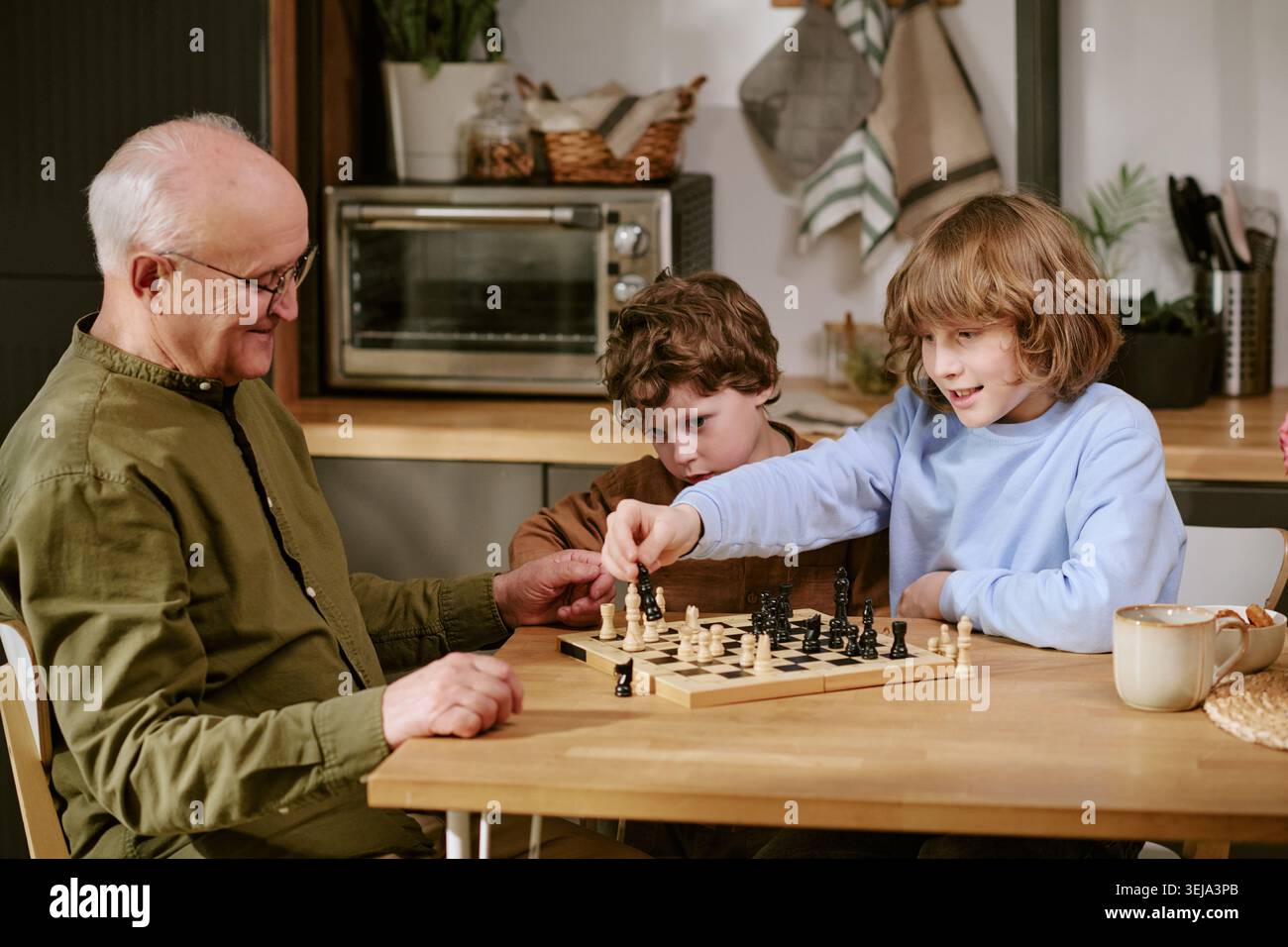 Senior-Mann, der Kindern Schach zu Hause beibringt Stockfoto