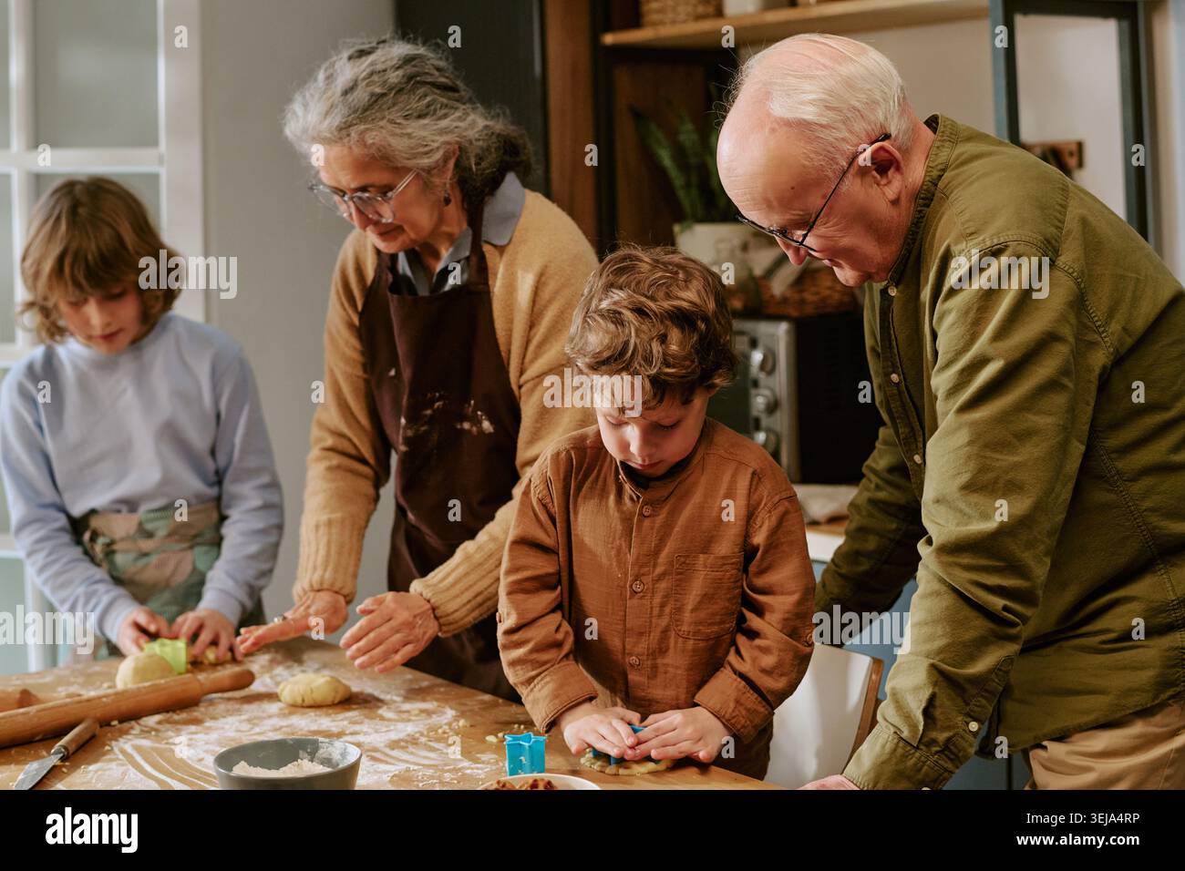 Seniorenpaar und Kinder backen zusammen für Familienbindung Stockfoto