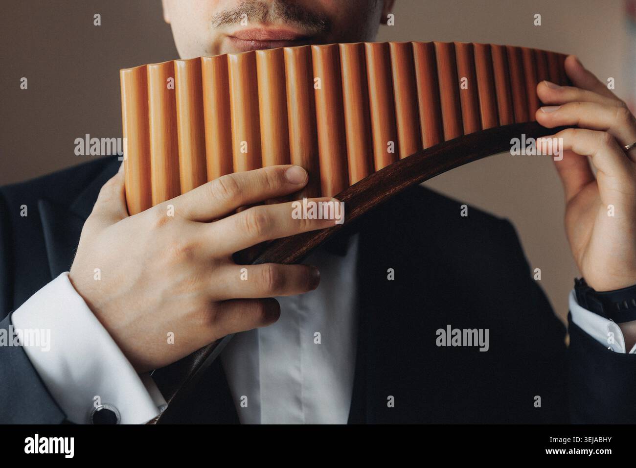 Der Mann spielt Holzflöte mit fokussiertem Ausdruck Stockfoto
