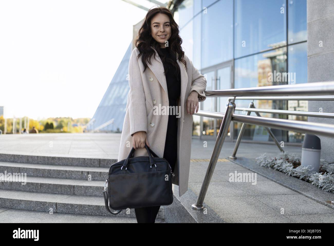 Eine Anwältin mit Aktenkoffer steht neben einem Bürogebäude Stockfoto