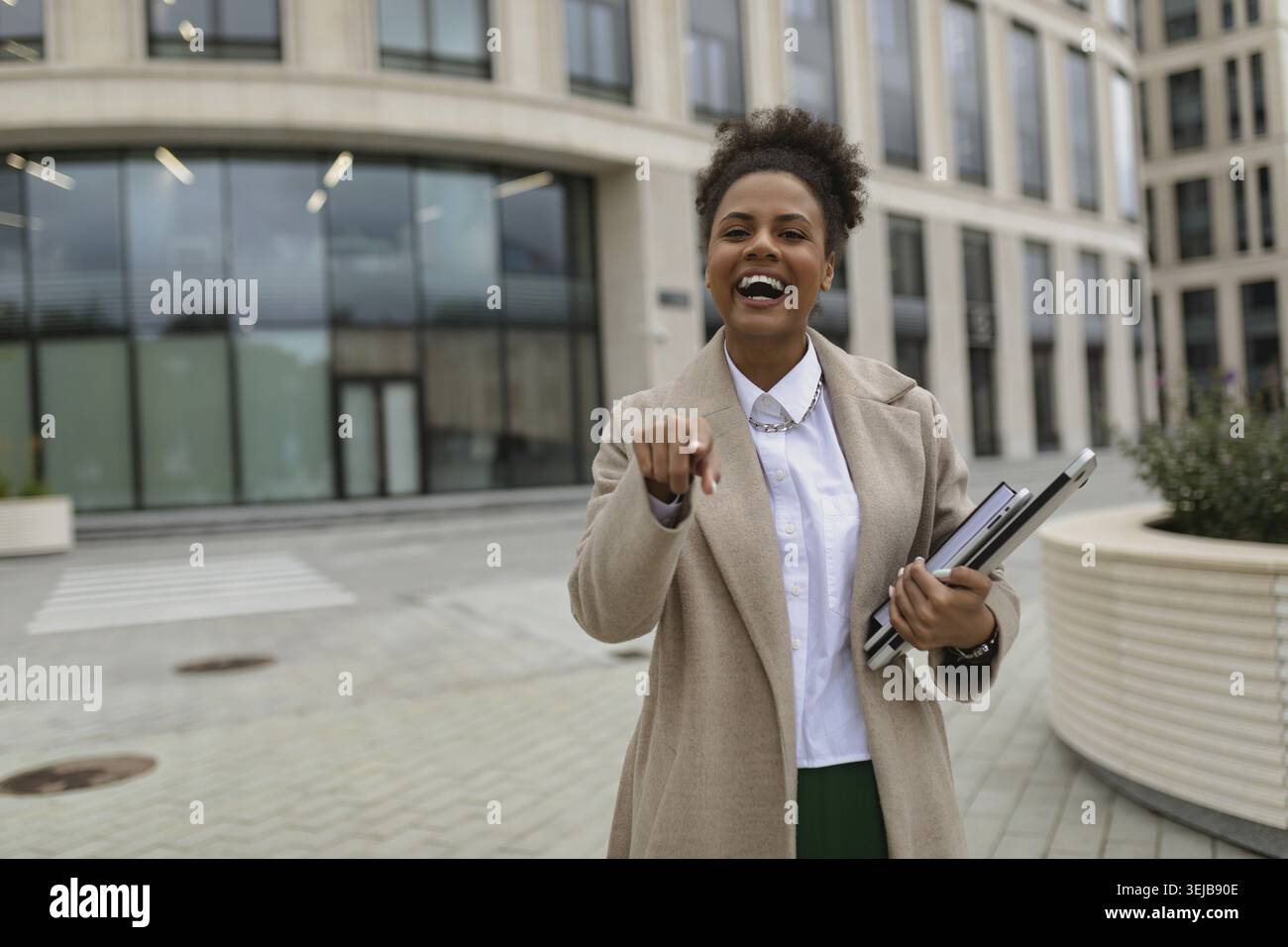 Zufriedene Geschäftsfrau afroamerikanerin mit freudigen Emotionen zeigt ihren Finger mit einem breiten Lächeln nach vorne Stockfoto