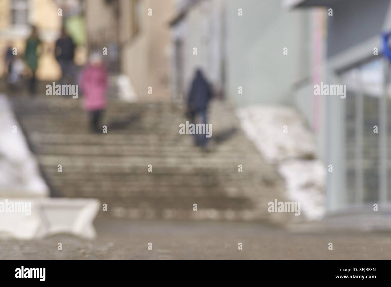 Verschwommene urbane Straßenszene mit Menschen auf Stufen im winterlichen Stadtbild Stockfoto