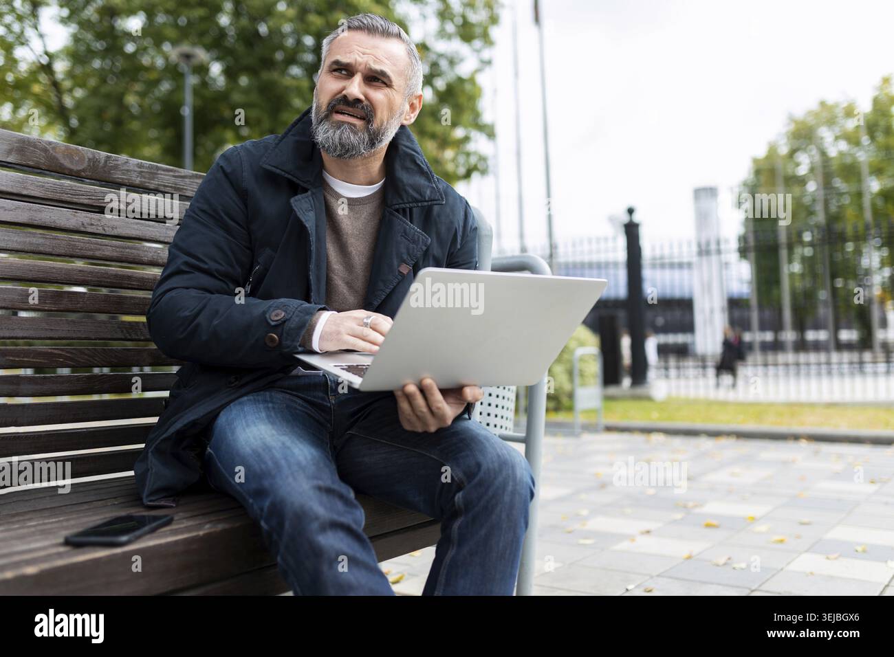 Grauhaariger, reifer Mann mit Laptop draußen Stockfoto