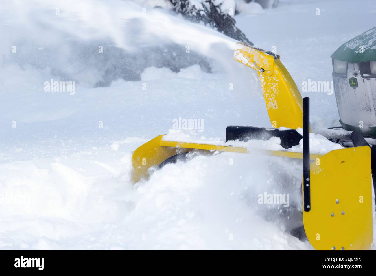 Spirit River, Alberta, Kanada - 27. Dezember 2025: John Deere Kompakttraktor mit Schneefräse pflügt Schnee und reinigt die Zufahrt in ländlichen Gebieten Stockfoto