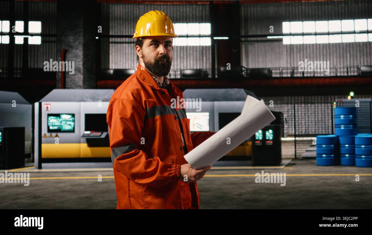 Der Maschinenbauingenieur untersucht in einer modernen Werkstatt die Baupläne und Schaltkreispläne. Die Lagerumgebung hebt präzise Messungen für Großmaschinen hervor. Stockfoto