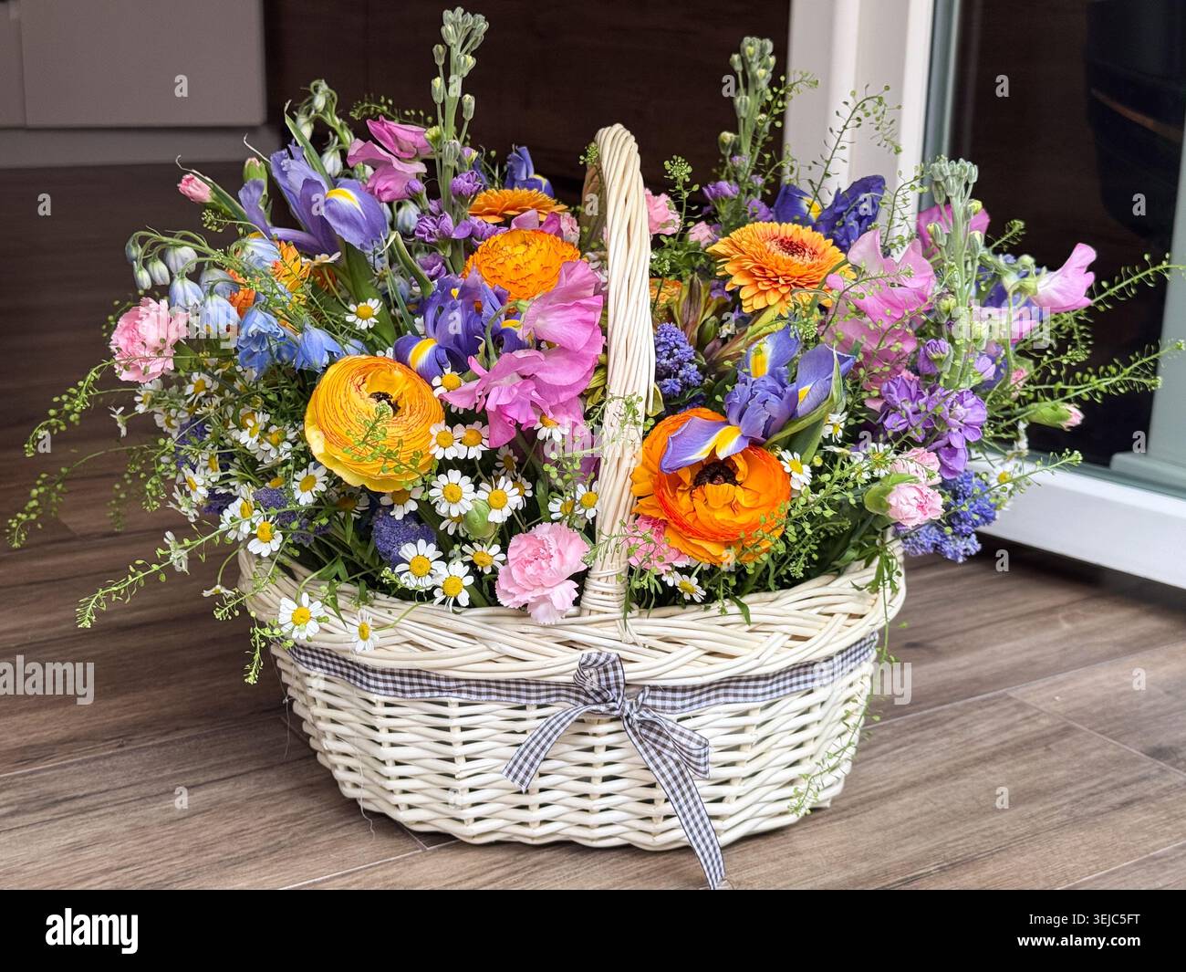 Reichlich farbenfrohe Ranunkeln Iris Gerbera Gänseblümchen Korb Stockfoto