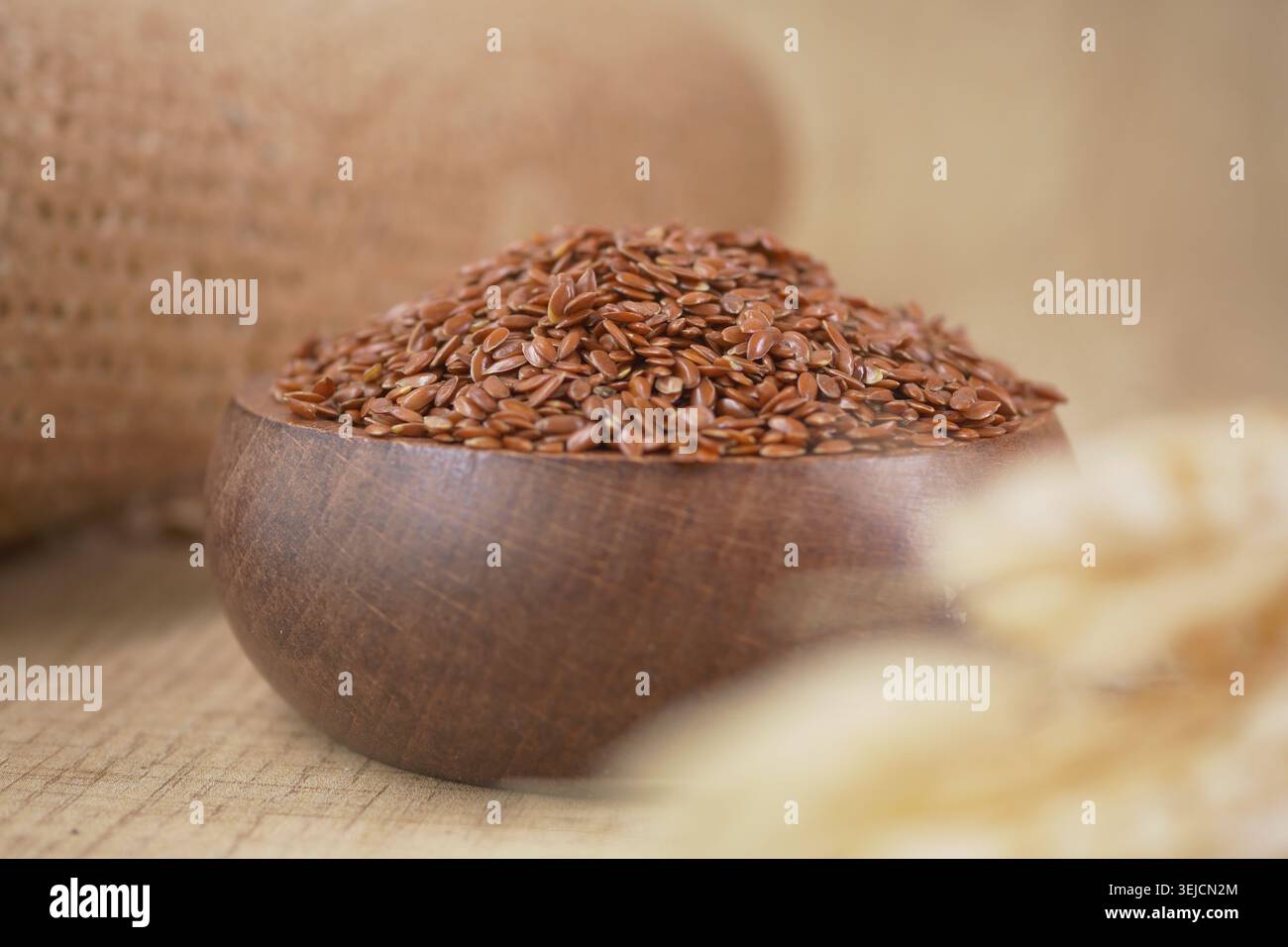 Flachssamen in einer Holzschale auf einem Tisch mit Stoff Stockfoto