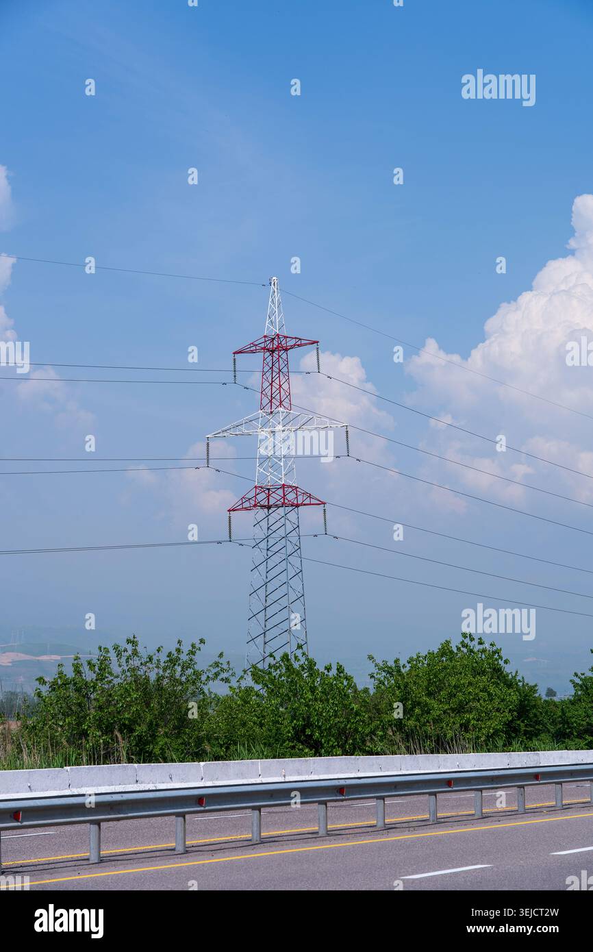 Unterstützung von Stromleitungen in der Nähe einer Autobahn vor einem Hintergrund von Bergen, Himmel und Wolken. Konzept: Elektrizität in den entlegensten Teilen des Landes Stockfoto