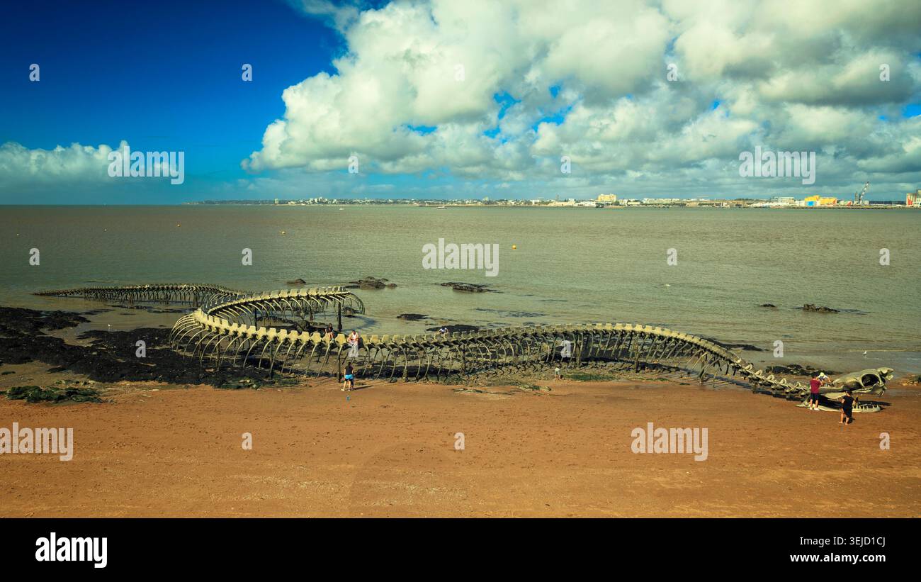 Saint-Michel-Chef-Chef, Frankreich - 19.08.2023: Massive dunkle, rippenartige Struktur, die am Ufer in der Nähe einer Küstenstadt unter bewölktem Himmel ruht Stockfoto