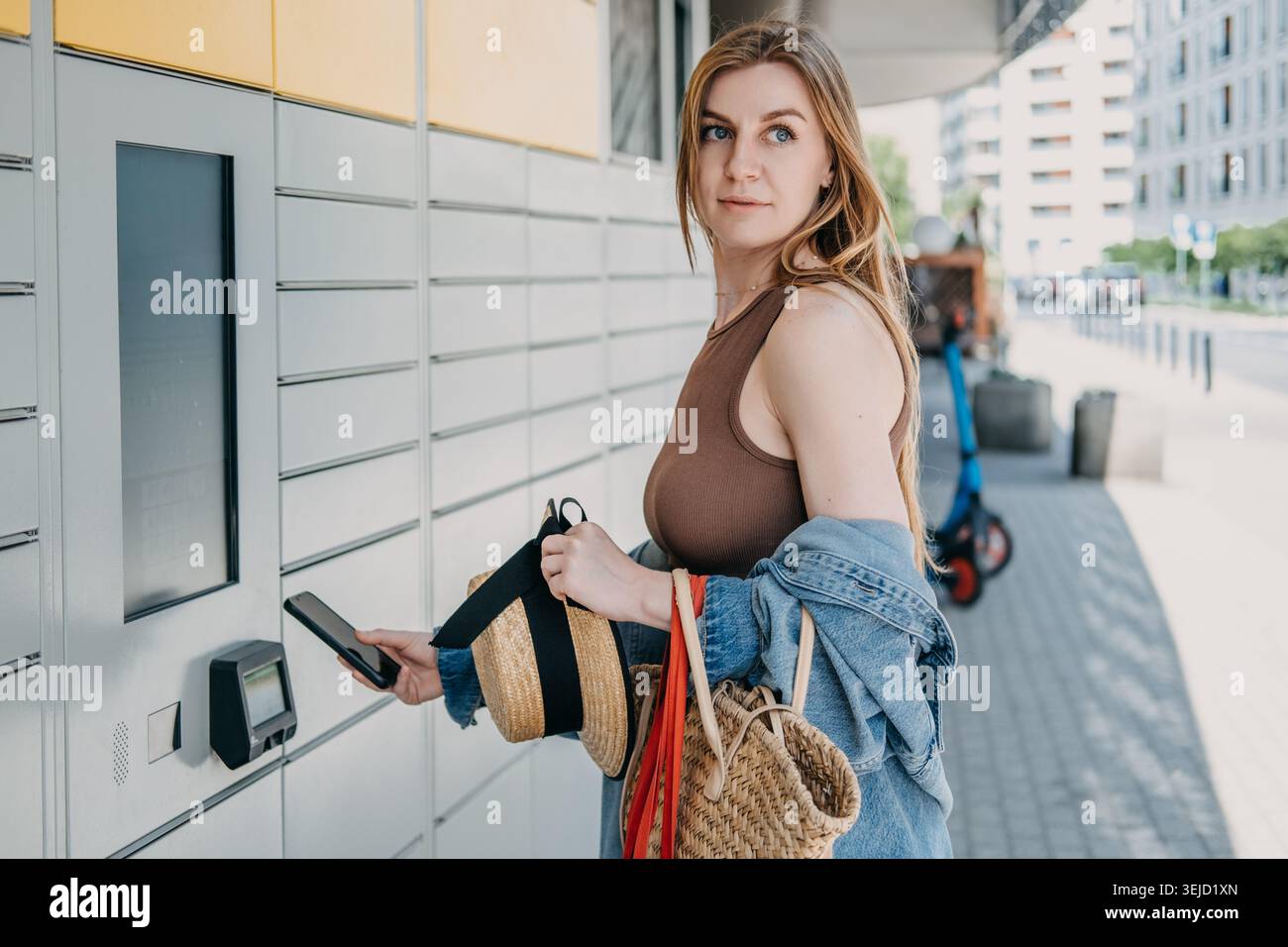 Die Frau hält das Smartphone in der Nähe von automatisierten Paketterminals und Einkaufstaschen. Intelligente Infrastruktur für den Einzelhandel in Städten, Integrationsdienst für städtische Technologien Stockfoto