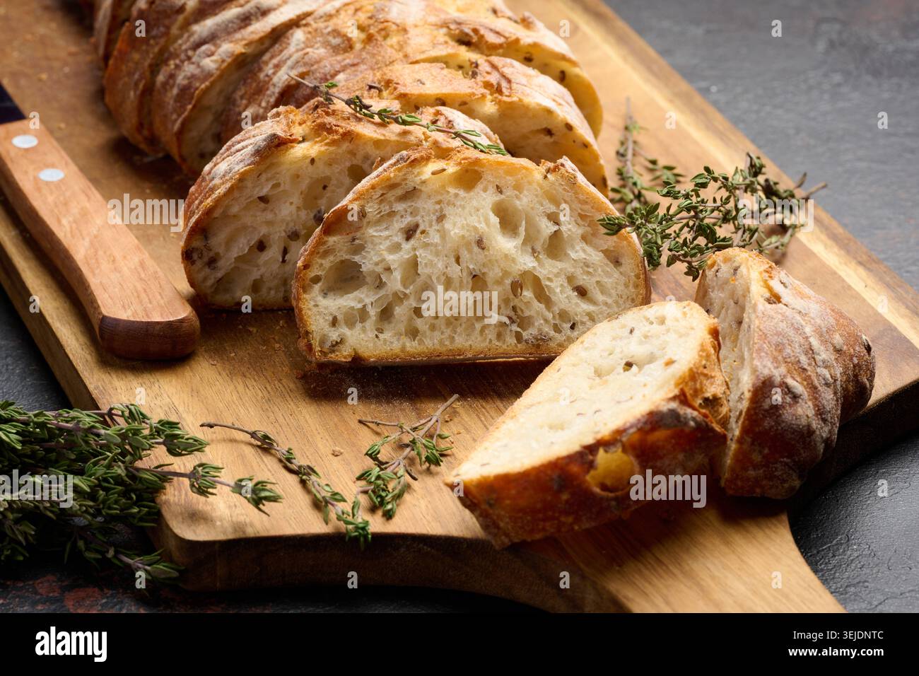 Geschnittene ​​baguette mit Flachs und Gewürzen auf einem hölzernen Schneidebrett Stockfoto