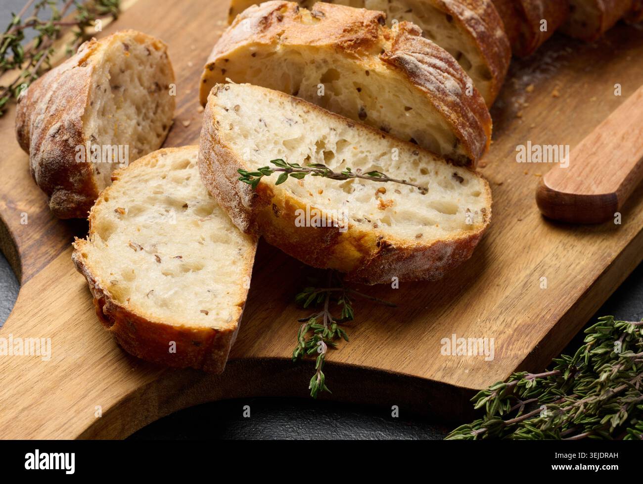 Geschnittene ​​baguette mit Flachs und Gewürzen auf einem hölzernen Schneidebrett Stockfoto