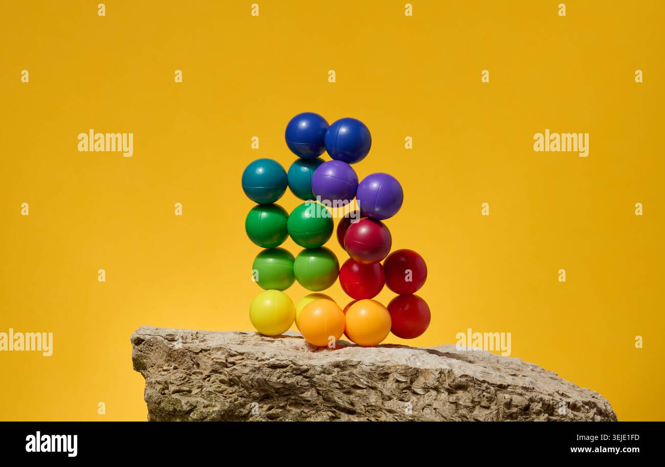 Abstrakter Hintergrund mit mehrfarbigen Kunststoffkugeln auf gelbem Hintergrund, eine Bühne zur Demonstration von Kosmetik und Prod Stockfoto