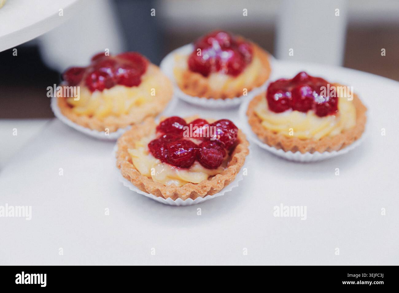 Vier kleine Torten sitzen auf einer weißen Oberfläche Stockfoto