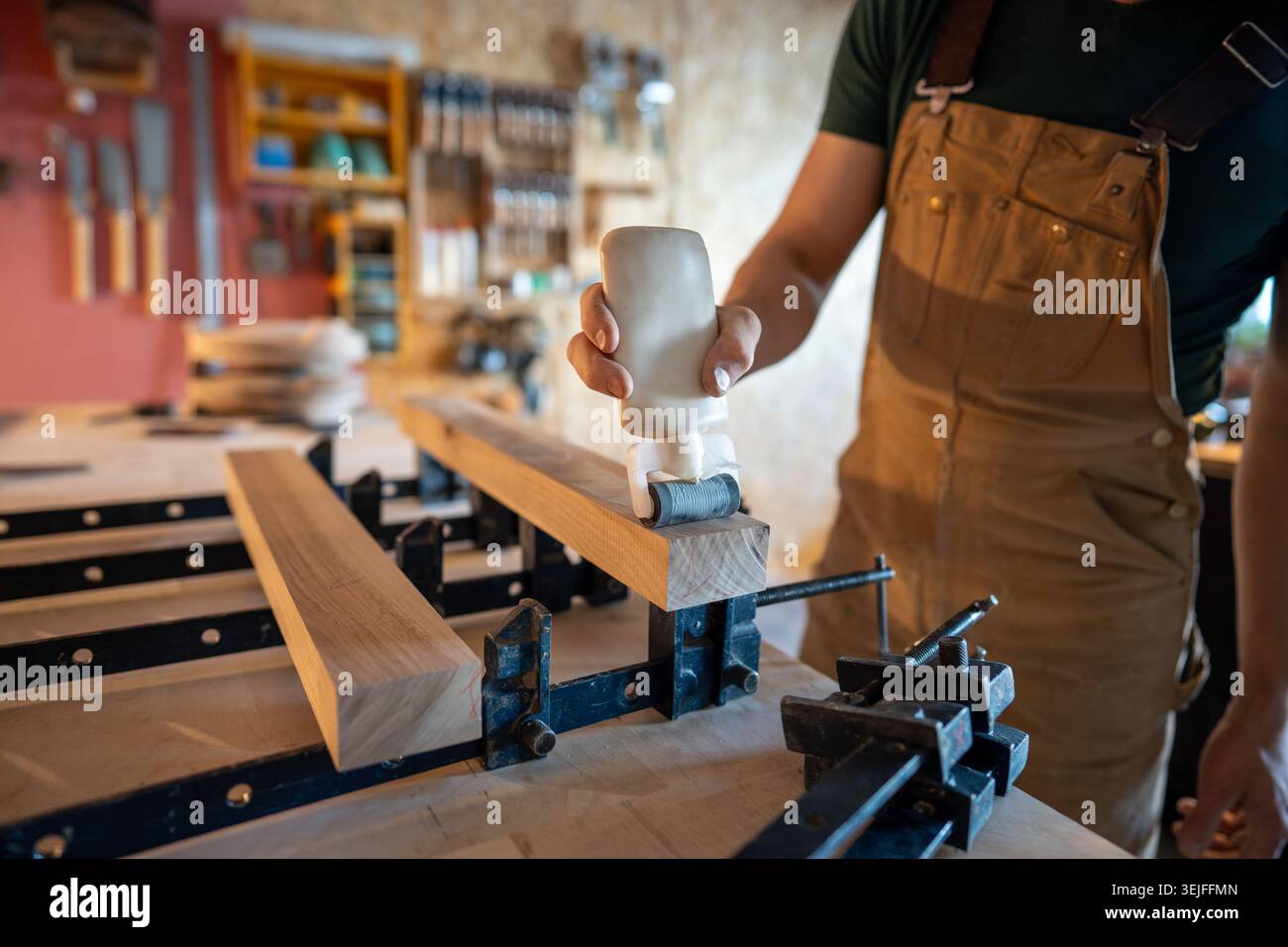 Tischlerhandauftragen von Leim auf Holzbalkenoberflächen Vorbereitung auf das Einspannen in große Bretter Stockfoto
