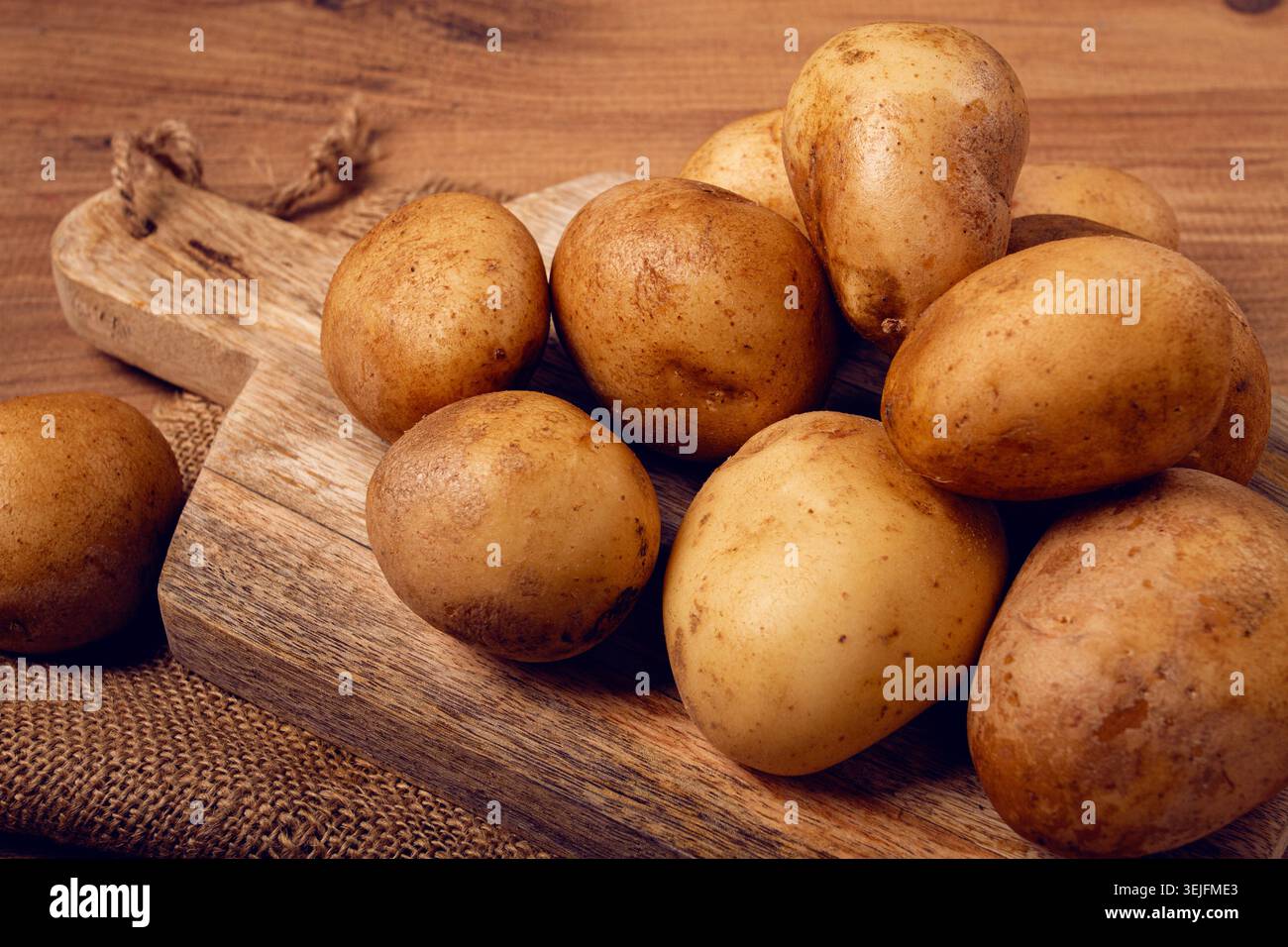 Rohe Kartoffeln, verstreut auf einem Schneidebrett, Nahaufnahme, keine Leute, Stockfoto
