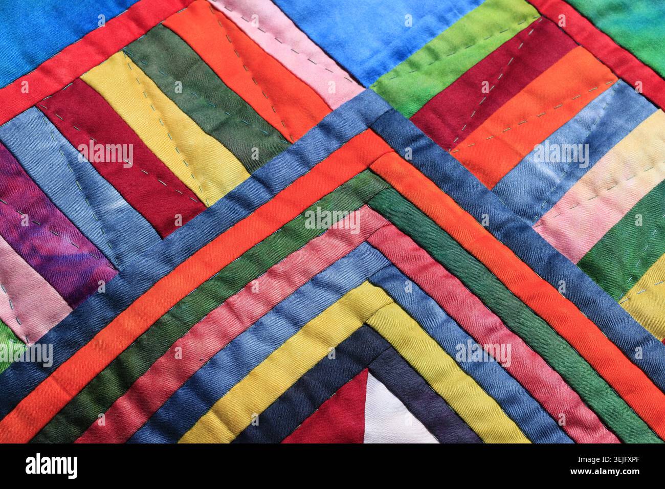 Dynamische, farbenfrohe Patchwork-Steppstruktur aus handgefärbten Baumwollstreifen Stockfoto