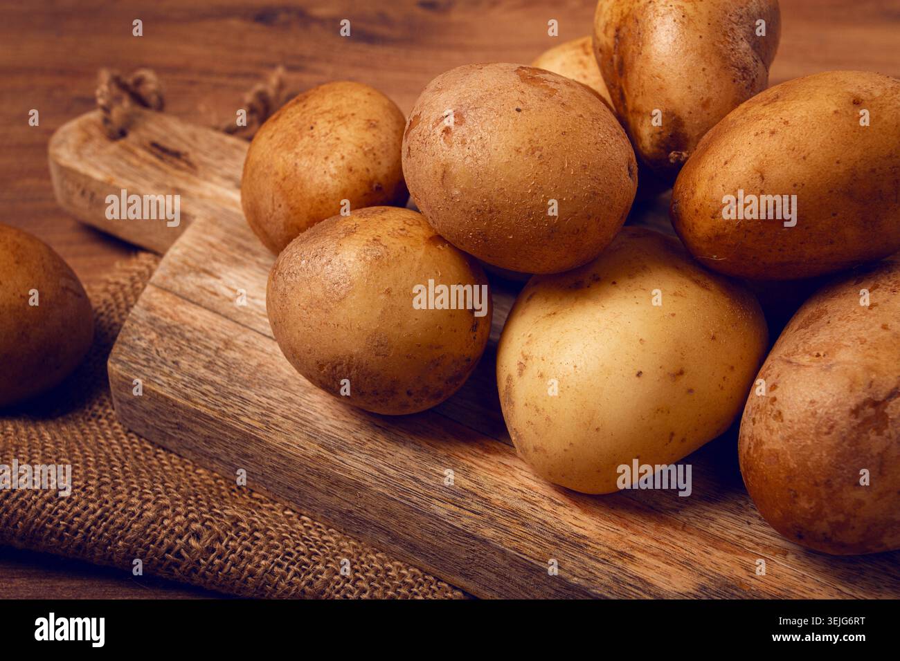 Rohe Kartoffeln, verstreut auf einem Schneidebrett, Nahaufnahme, keine Leute, Stockfoto