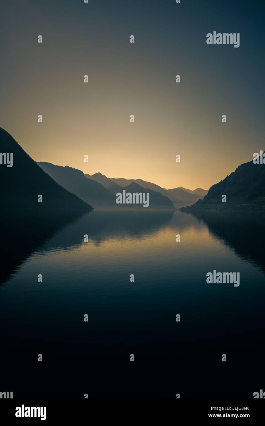 Dämmerung über dem Idro-See in Norditalien, mit ruhigem Wasser, Bergsilhouetten und Reflexionen unter einem verblassenden Abendhimmel. Stockfoto