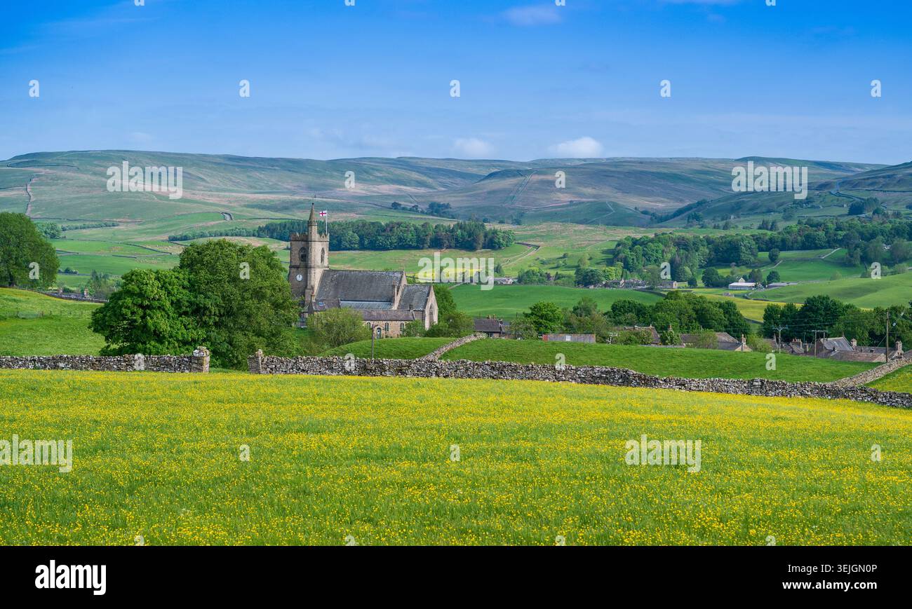 St. Margarets Church, Hawes, im Frühsommer, mit Wildblumenwiese vor Staggs fiel hinter. North Yorkshire, Großbritannien. Stockfoto