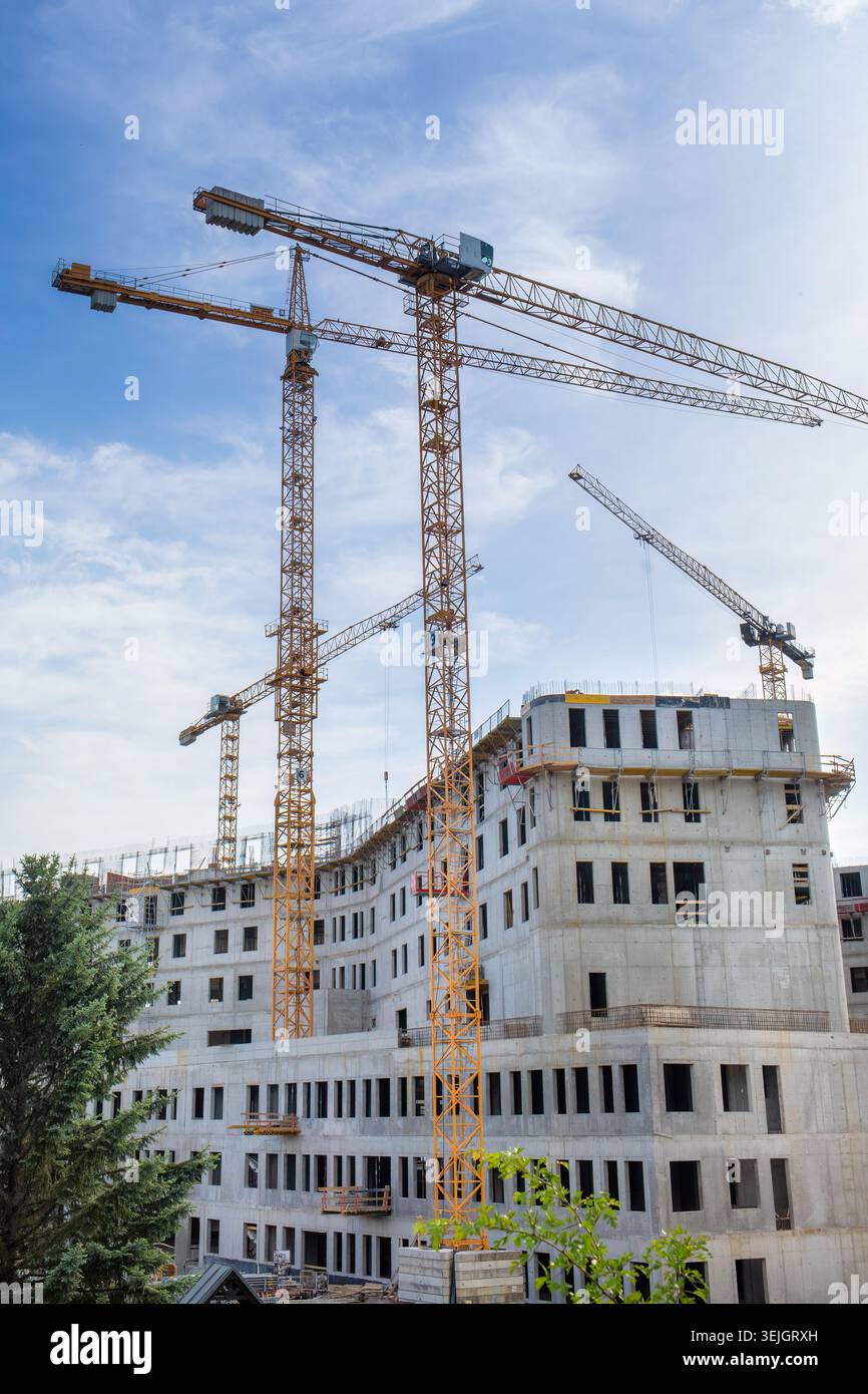Turmkräne über einem großen Wohngebäude aus Beton im Bau Stockfoto