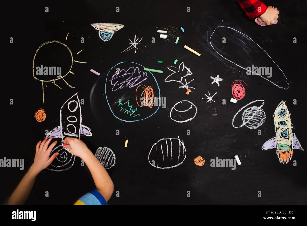 Die Kinder zeichnen eine Rakete und einen Raum auf eine Tafel. Vorschulkind in Kreativität im Haushalt. Internationaler Weltraumtag Stockfoto