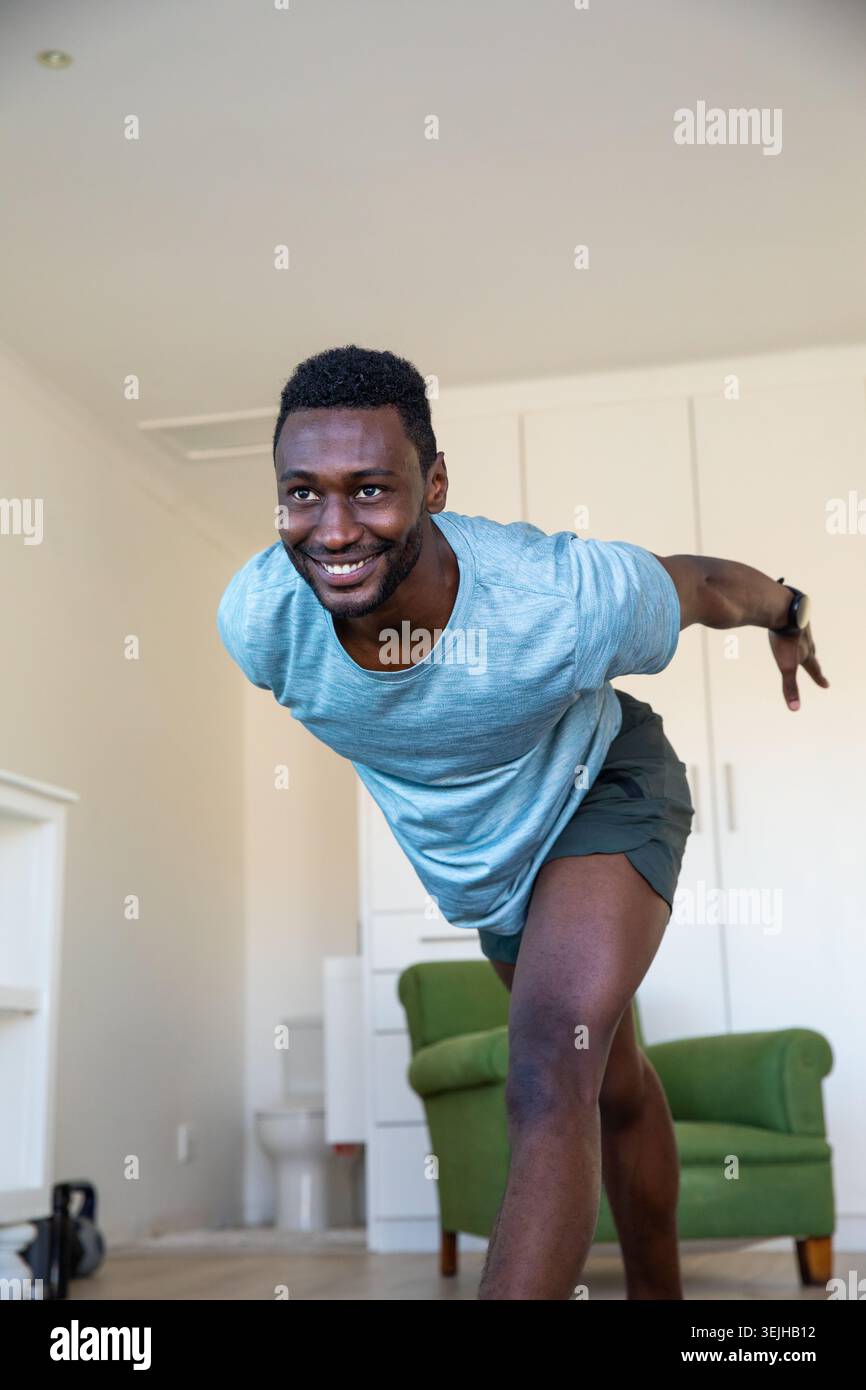 Afroamerikaner in Sportbekleidung, der zu Hause mit einer Kettlebell Balanceübung auf einem Bein ausübt. Fitness, Wellness, Home Wor Stockfoto