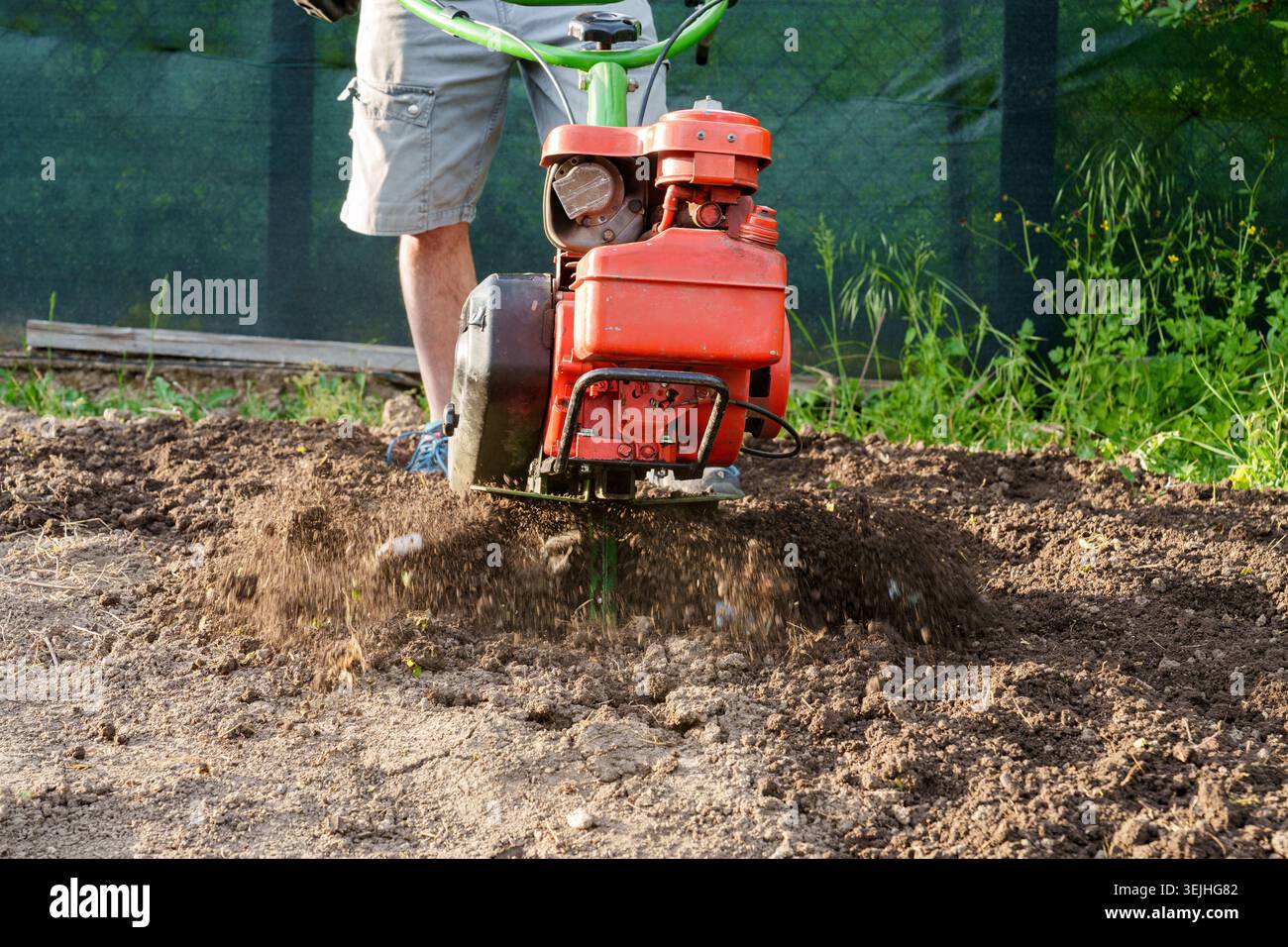 Mann mit Motorgrubber, um Erde im Garten aus nächster Nähe zu lösen Stockfoto