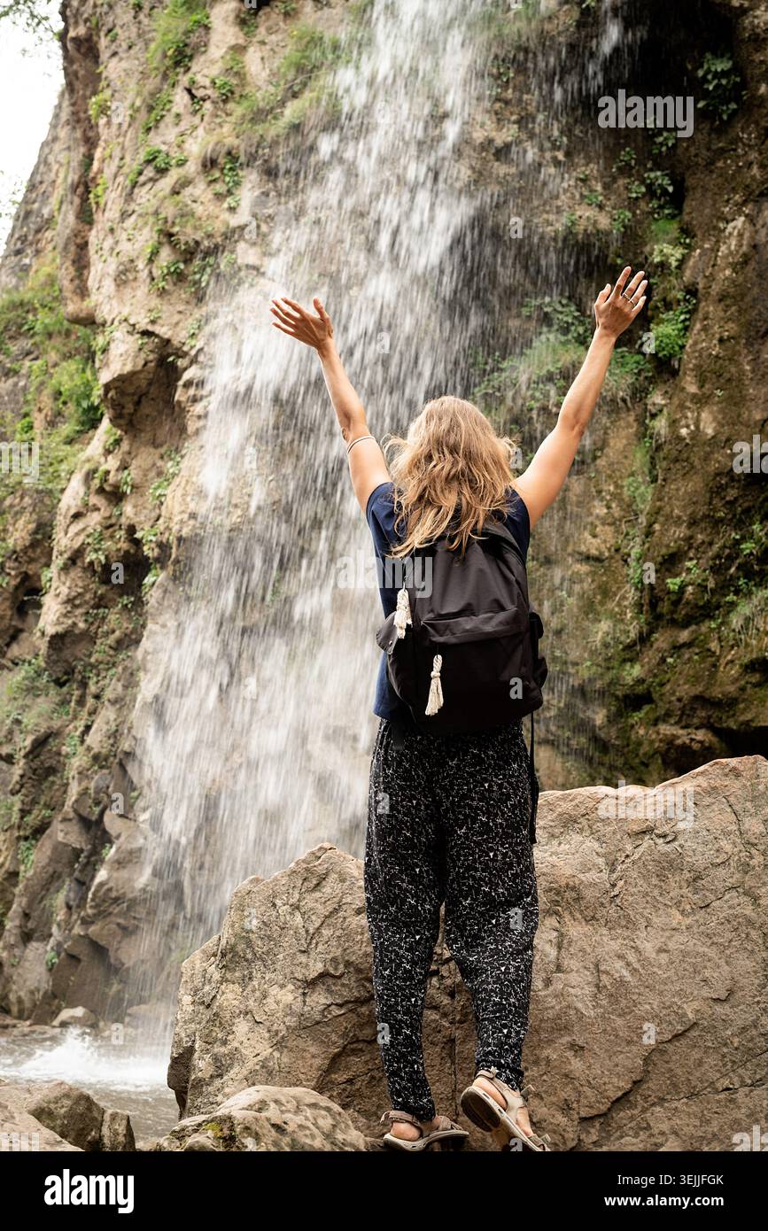 Frau, die auf der Brücke steht und auf den wunderschönen Wasserfall blickt Stockfoto
