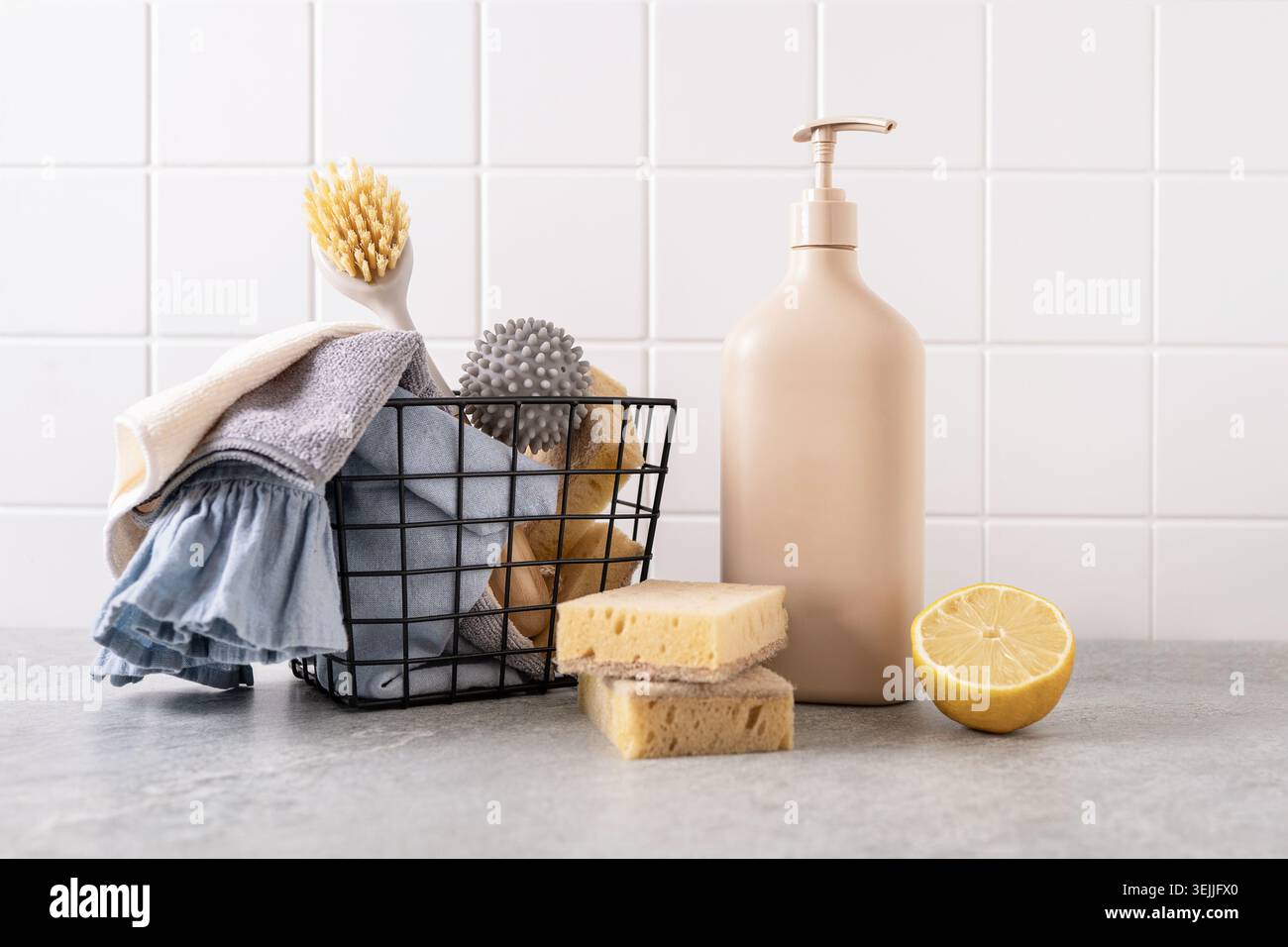 Umweltfreundliche Reinigungsmittel im Drahtkorb mit wiederverwendbaren Tüchern Schwämmchen Bürste und nachfüllbarer Flasche auf der Küchenarbeitsplatte. Nachhaltige Hausreinigung Stockfoto