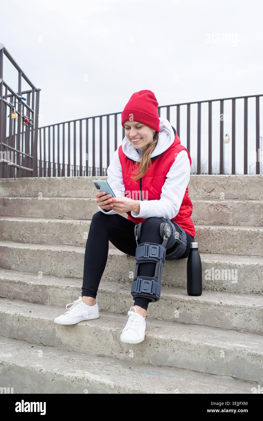 Frau, die Knie- oder Orthesen nach Beinoperationen trägt, auf Treppen sitzt Stockfoto