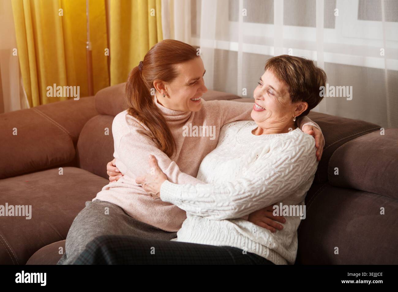 Glückliche Seniorin Mutter und Erwachsene Tochter umarmen sich drinnen. Familienzeit. Stockfoto