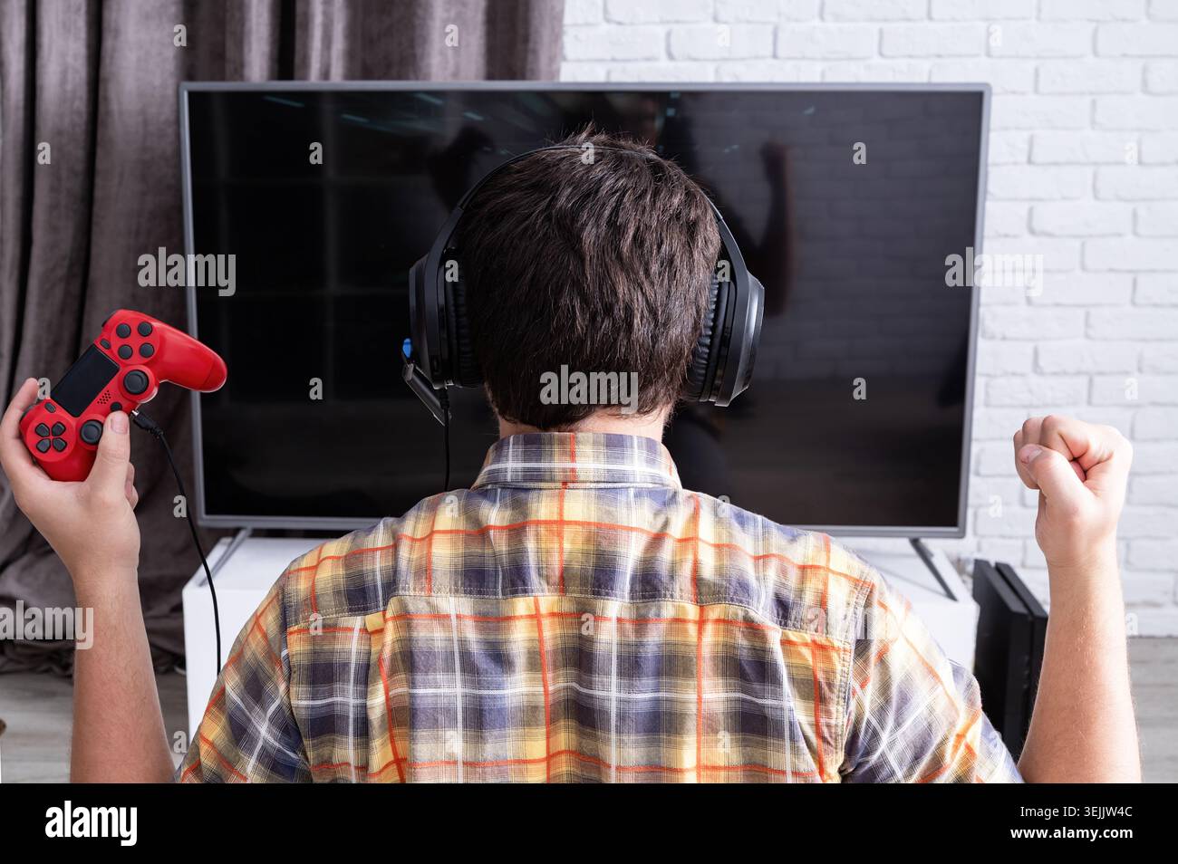 Rückansicht eines jungen Mannes, der zu Hause Videospiele spielt Stockfoto