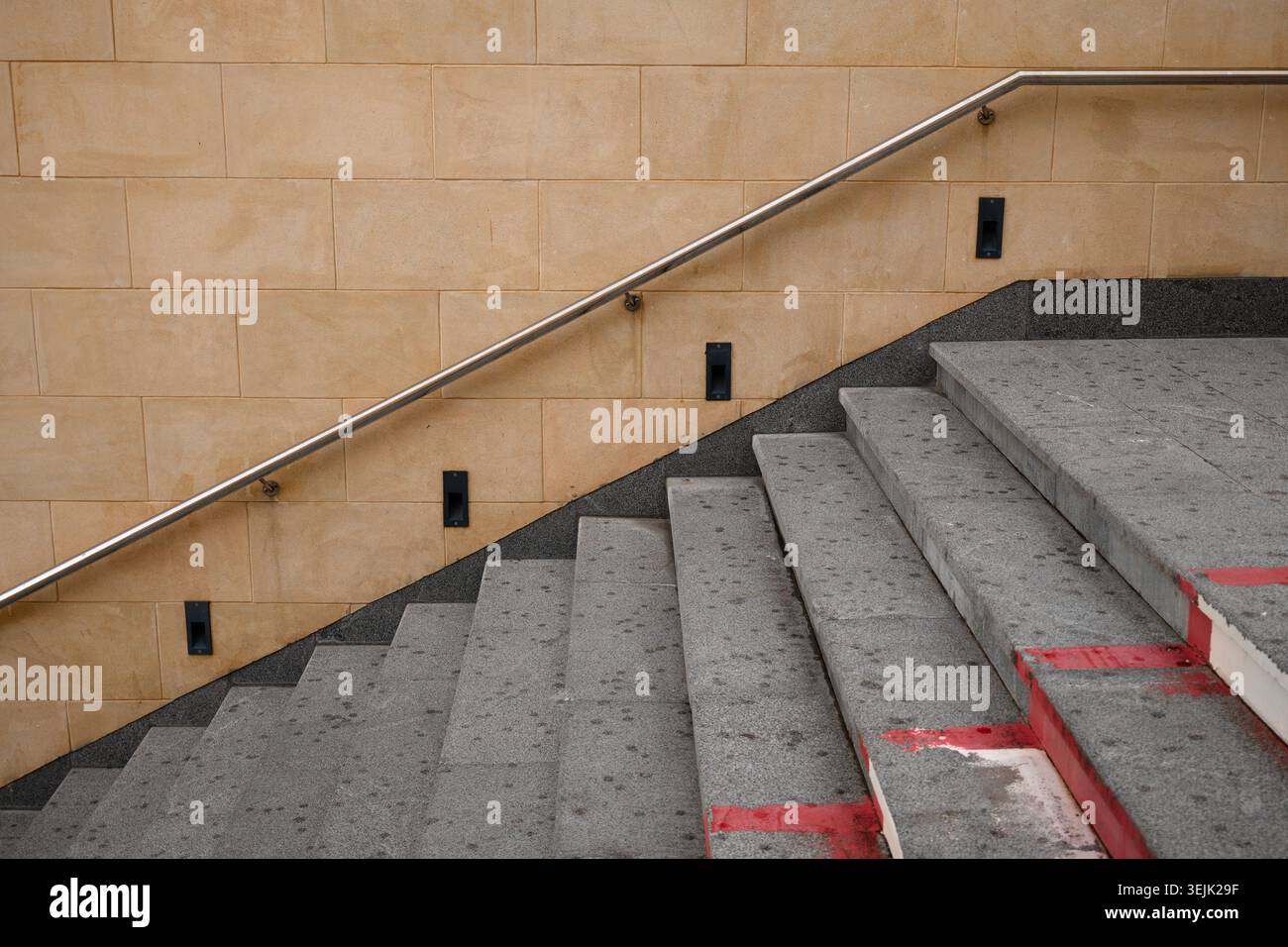 Hochwinkelaufnahme von architektonischen Betonstufen mit Sicherheitsgeländer aus Metall und beigefarbener Wand Stockfoto