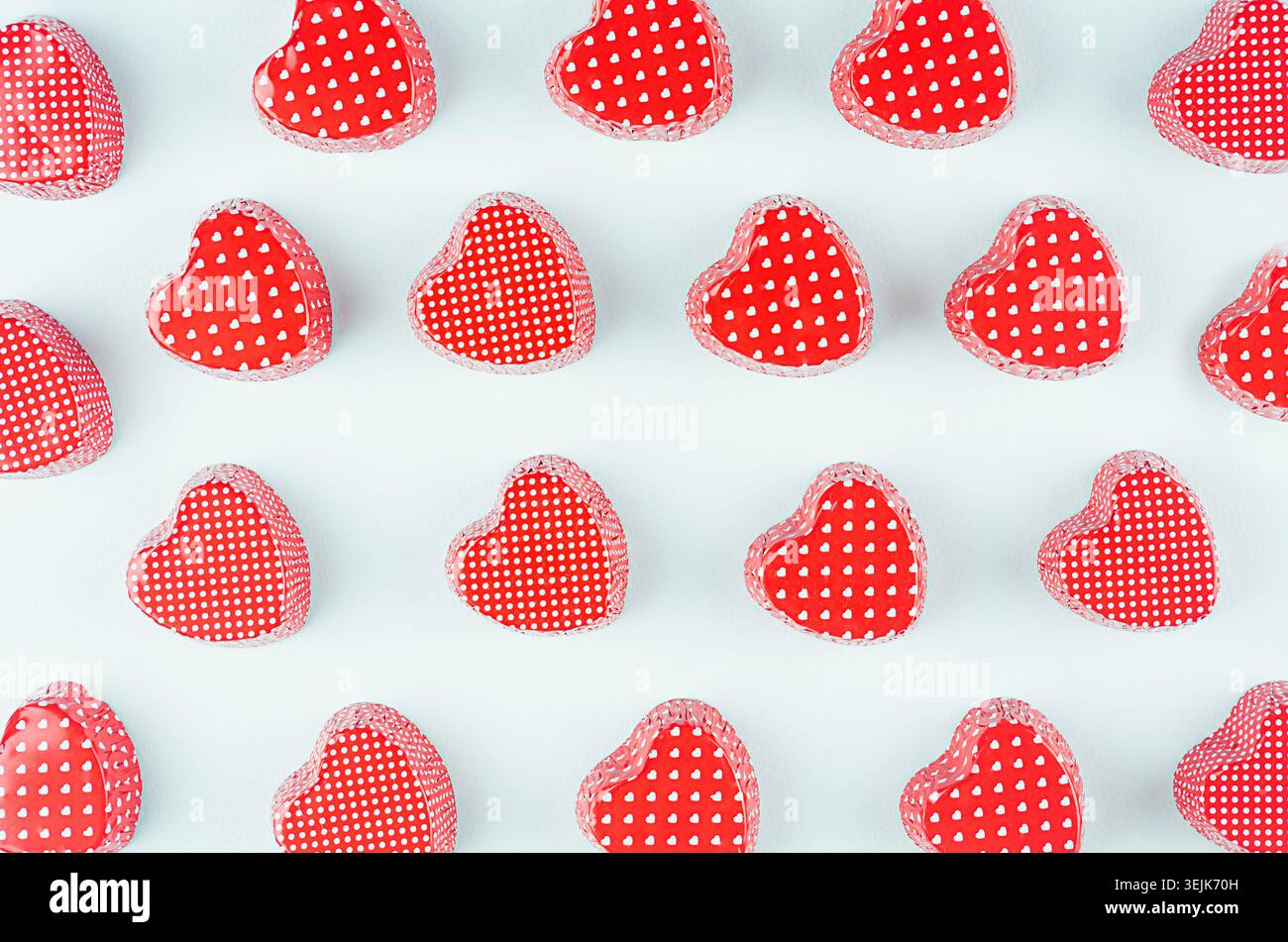 Hellrote Herzen auf mintfarbenem Pastellpapierhintergrund. Valentinstag Jugend Design Konzept Kunst. Stockfoto