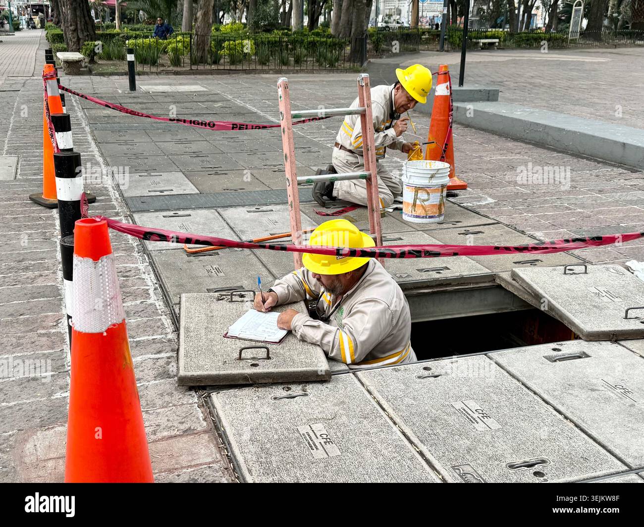 Versorgungsarbeiter überprüfen die unterirdische Infrastruktur während der Wartungsarbeiten auf einem Bürgersteig in Mexiko-Stadt, Mexiko Stockfoto