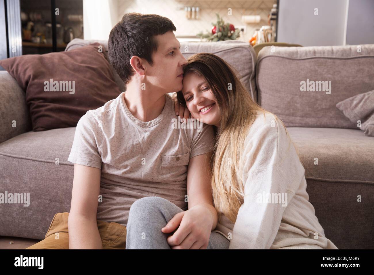 Familie hat Spaß, Zeit zu Hause zusammen zu verbringen. Ein liebevolles Paar sitzt auf dem Boden, umarmt und hat zu Hause Spaß Stockfoto