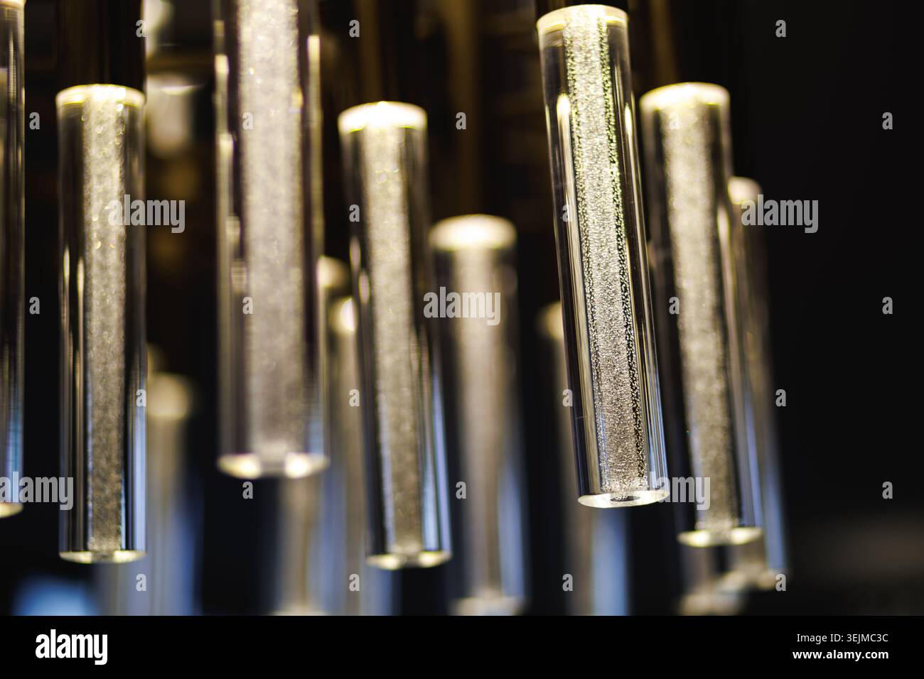 Moderner Kronleuchter mit leuchtenden Glasröhren gefüllt mit Luftblasen Stockfoto