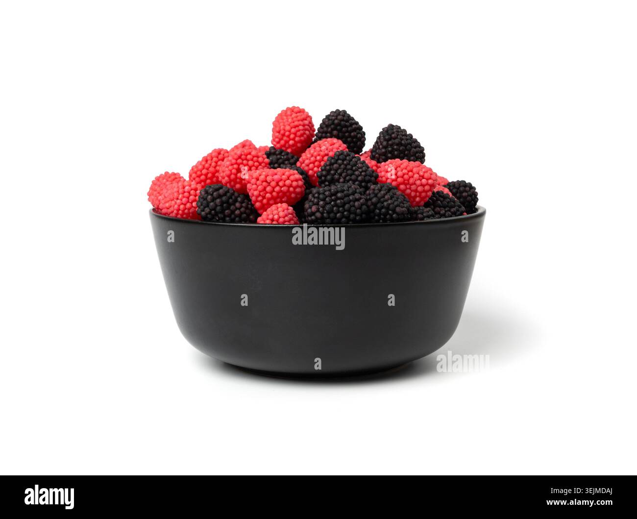 Gummibeeren in der Schüssel isoliert, Kaubeeren, Gelee Brombeeren, rote Gelatinesbonbons und schwarze Fruchtmarmelade bedeckt mit kleinem knusprigem Zucker Stockfoto