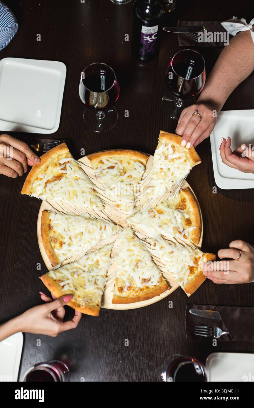 Blick auf Freunde, die Pizza an einem Restauranttisch teilen Stockfoto