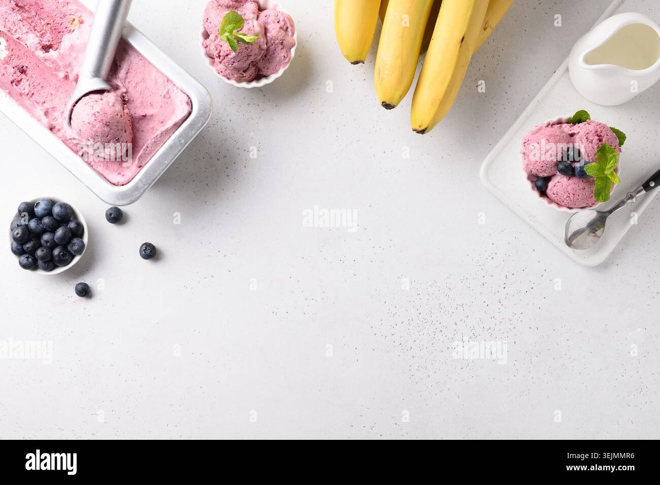 Hausgemachte Banane, Beeren Eis in Metallbehälter und Portion in Schüssel auf weiß. Blick von oben. Leerzeichen für Text. Stockfoto