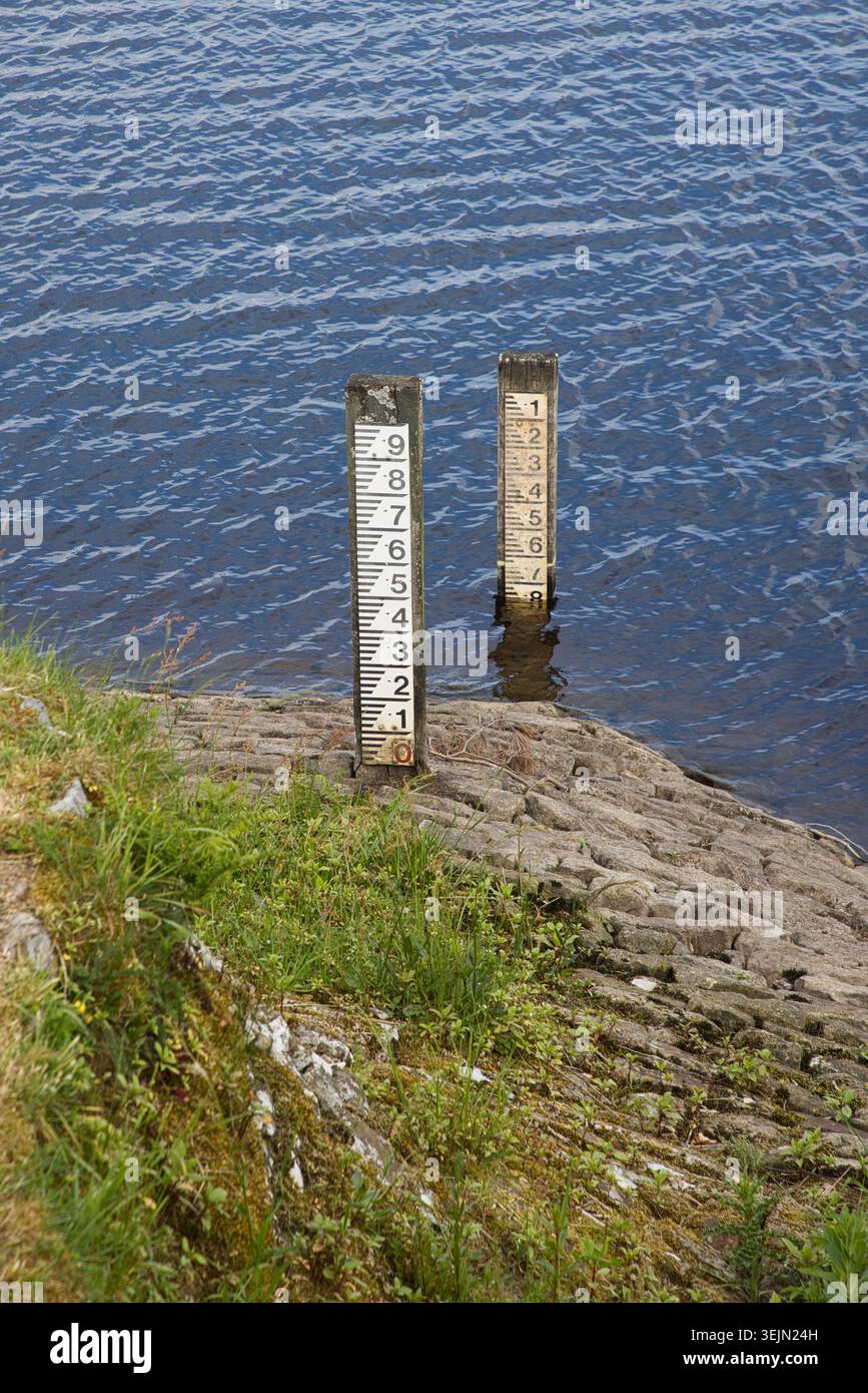 Zwei vertikale Wassertiefenmarkierungen stehen an der Steinfangmulde des Entwistle Reservoir, Lancashire, Großbritannien. Stockfoto