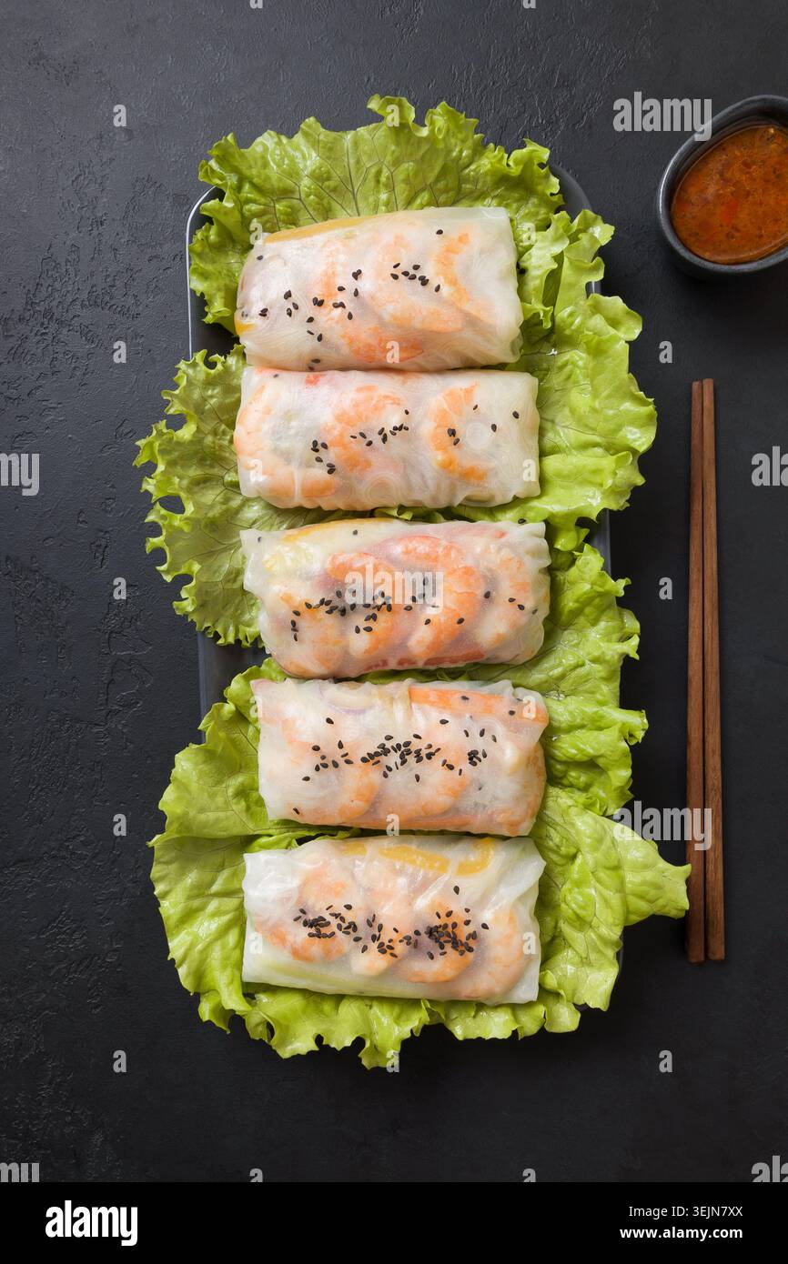 Vietnamesische Frühlingsrollen mit Gemüse, Garnelen in Reispapier auf Schwarz. Blick von oben. Asiatische Küche. Stockfoto
