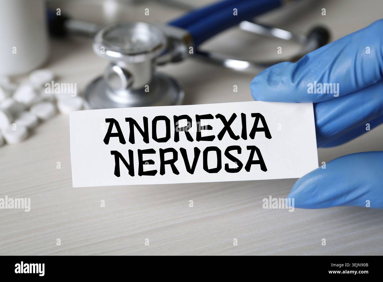 Doktor hält Karte mit den Worten Anorexia nervosa am Tisch, Nahaufnahme Stockfoto