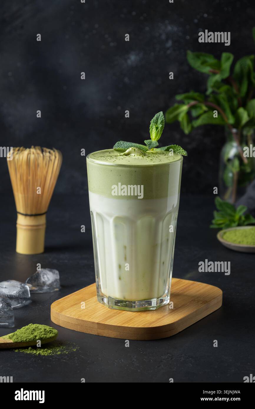 Ein Glas Dalgona Iced Matcha Tee auf Schwarz. Stockfoto