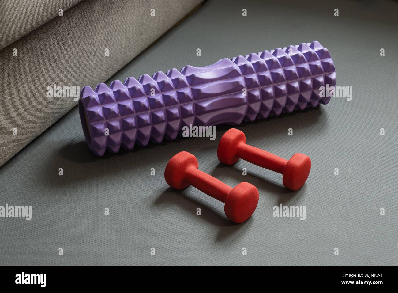 Schaumstoffrolle und Hantel auf Fitnessmatte Stockfoto