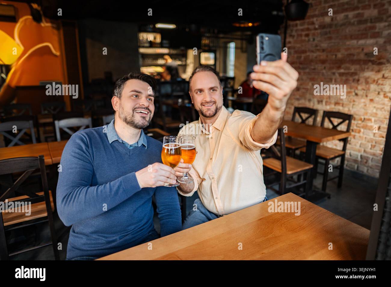Zwei Männer nehmen Selfie und toasten Bier in einem Pub Stockfoto