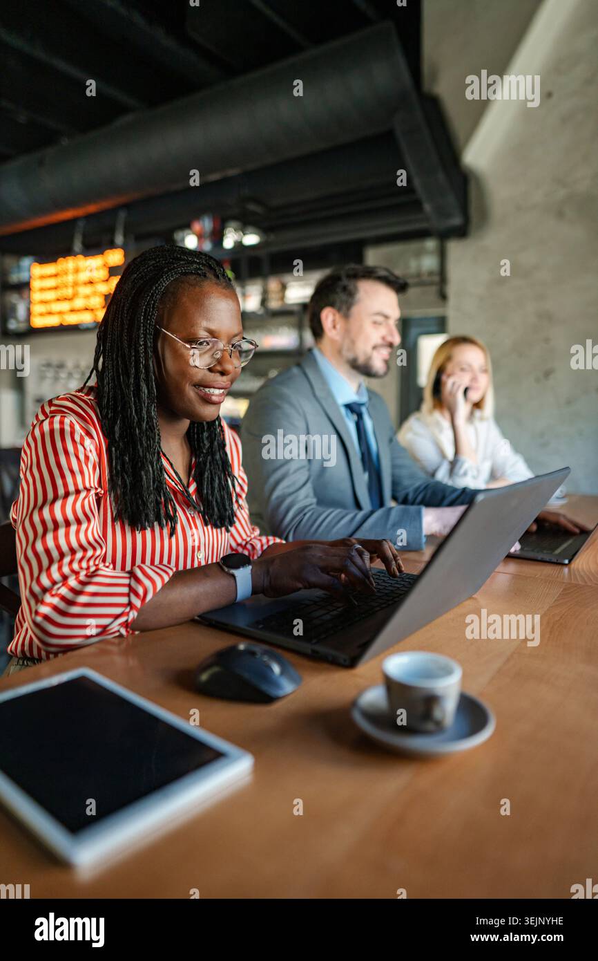 Vielfältige Geschäftsleute, die in einem modernen Café an Laptops arbeiten Stockfoto